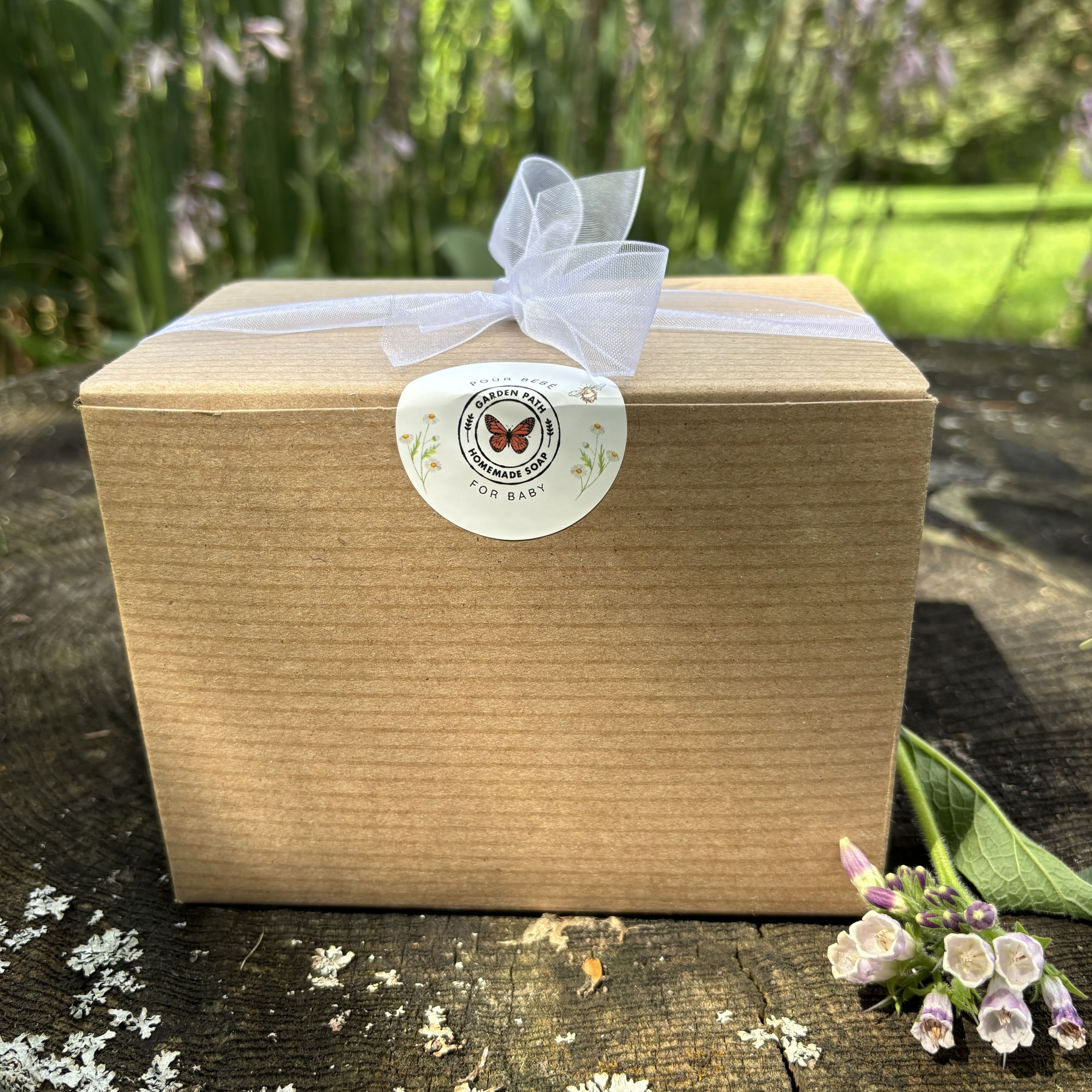 Garden Path Homemade Soap's Wiggle Baby Bundle packaged in a box with a ribbon tied around it with a butterfly logo sticker .