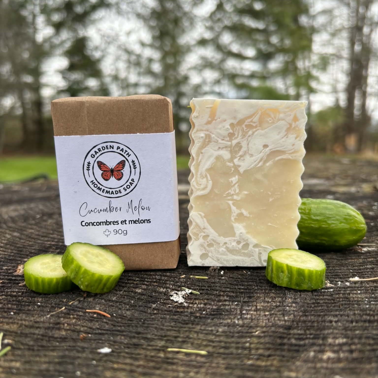 Cucumber Melon Bar of soap wrapped and unwrapped with cucumbers on a wooden surface outdoors. Garden Path Homemade Soap