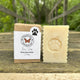 Dog soap bar and packaging with paw print design on a wooden surface outdoors by Garden Path Homemade Soap. 100% Natural Ingredients.