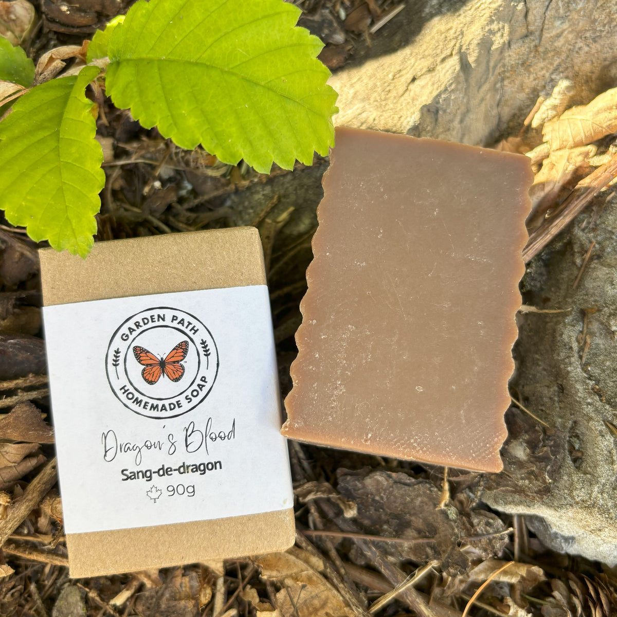 Dragon's Blood Bar Soap in an outdoor setting showing both wrapped and unwrapped bars. | Lightly Scented with Dragon's Blood Fragrance - Garden Path Homemade Soap