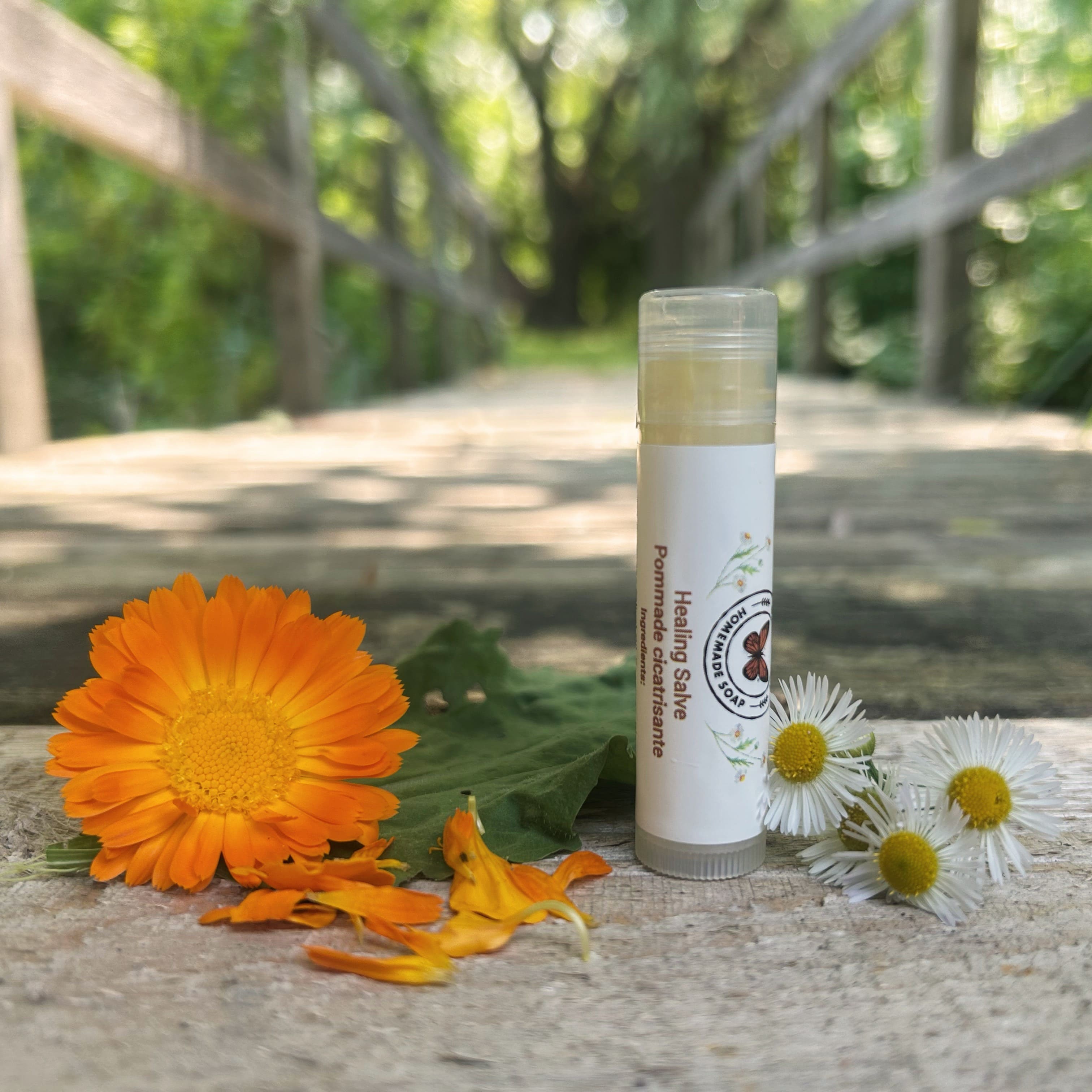 Tube of healing salve with flowers on a wooden surface . 100% Natural Ingredients & Essential Oils | Garden Path Homemade soap