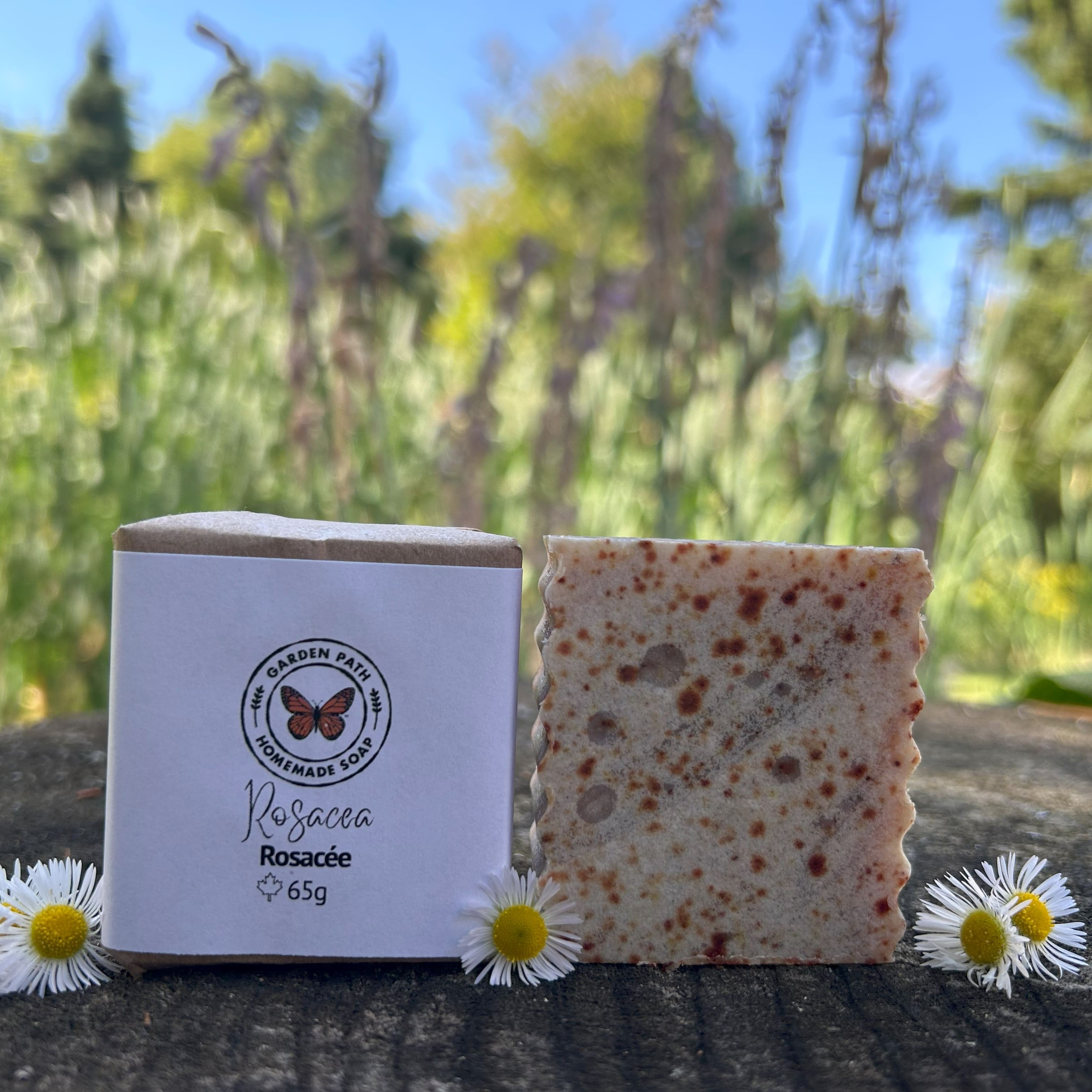 Rosacea Facial Bar of soap with packaging and flowers on a natural background by Garden Path Homemade Soap. 100% Natural Anti-Inflammatory Ingredients