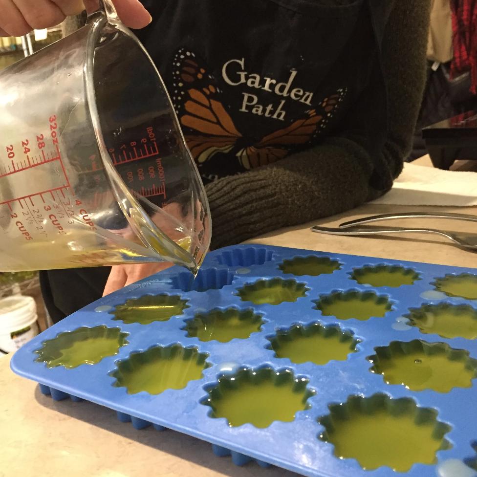 Person pouring liquid form of the foot balm into moulds.