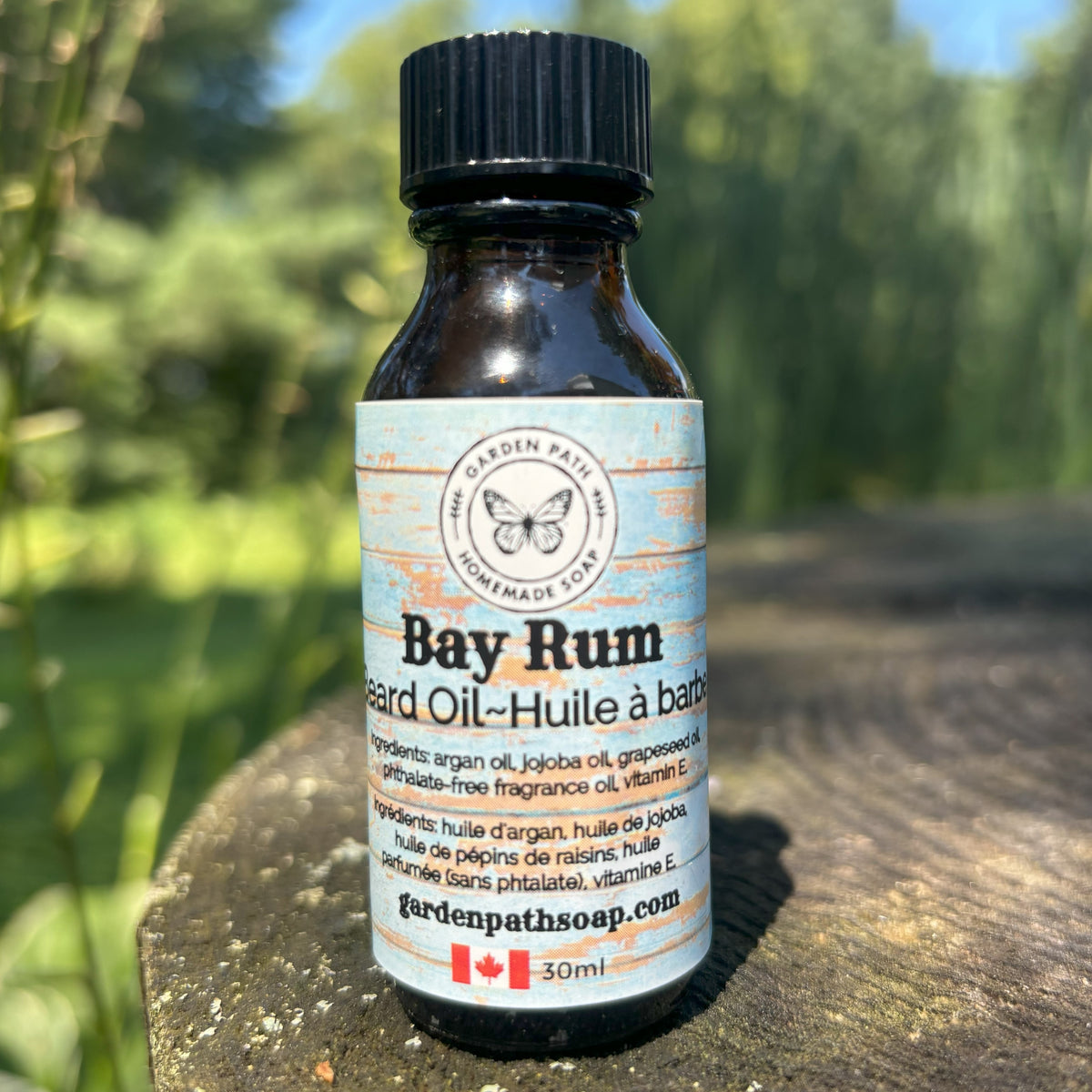 Bay Rum Beard Oil by Garden Path Homemade Soap sitting on a wooden surface with green natural back ground.