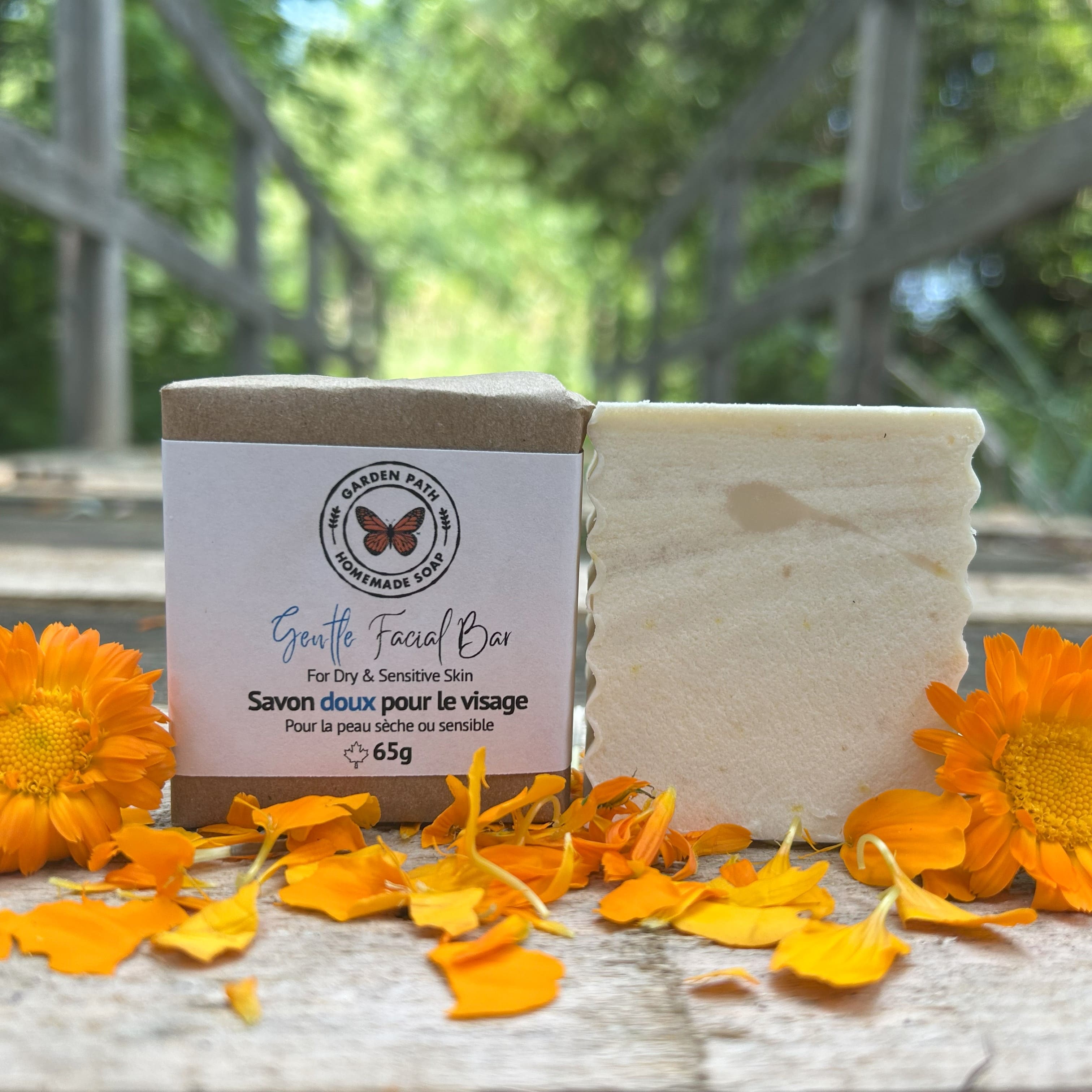 Gentle Facial Bar of soap (both wrapped and unwrapped) with calendula petals on a wooden surface by Garden Path Homemade Soap.  for dry, sensitive skin | 100% Natural Ingredients