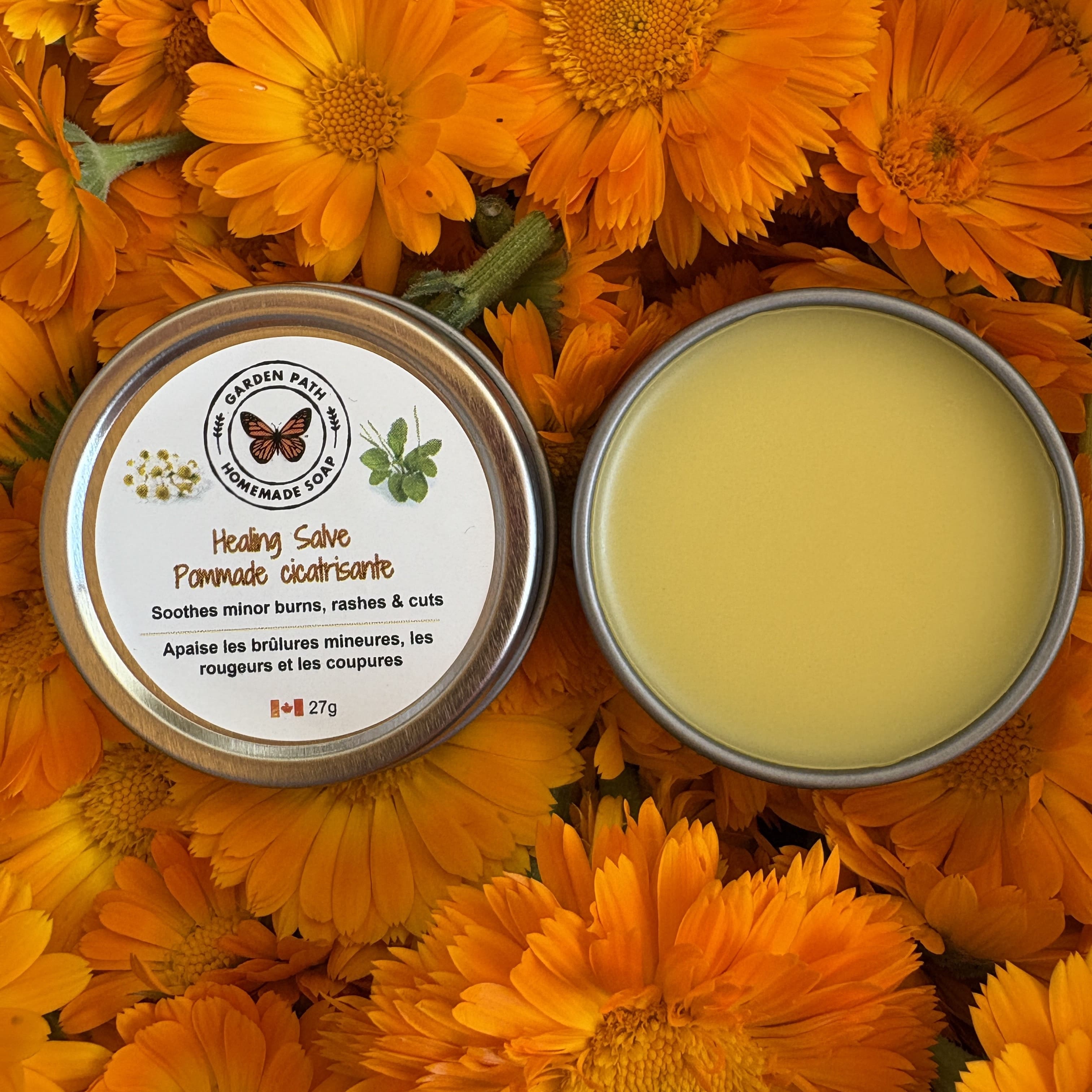 Healing salve in a tin surrounded by calendula flowers by Garden Path Homemade Soap. 100% Natural Ingredients & Essential Oils 