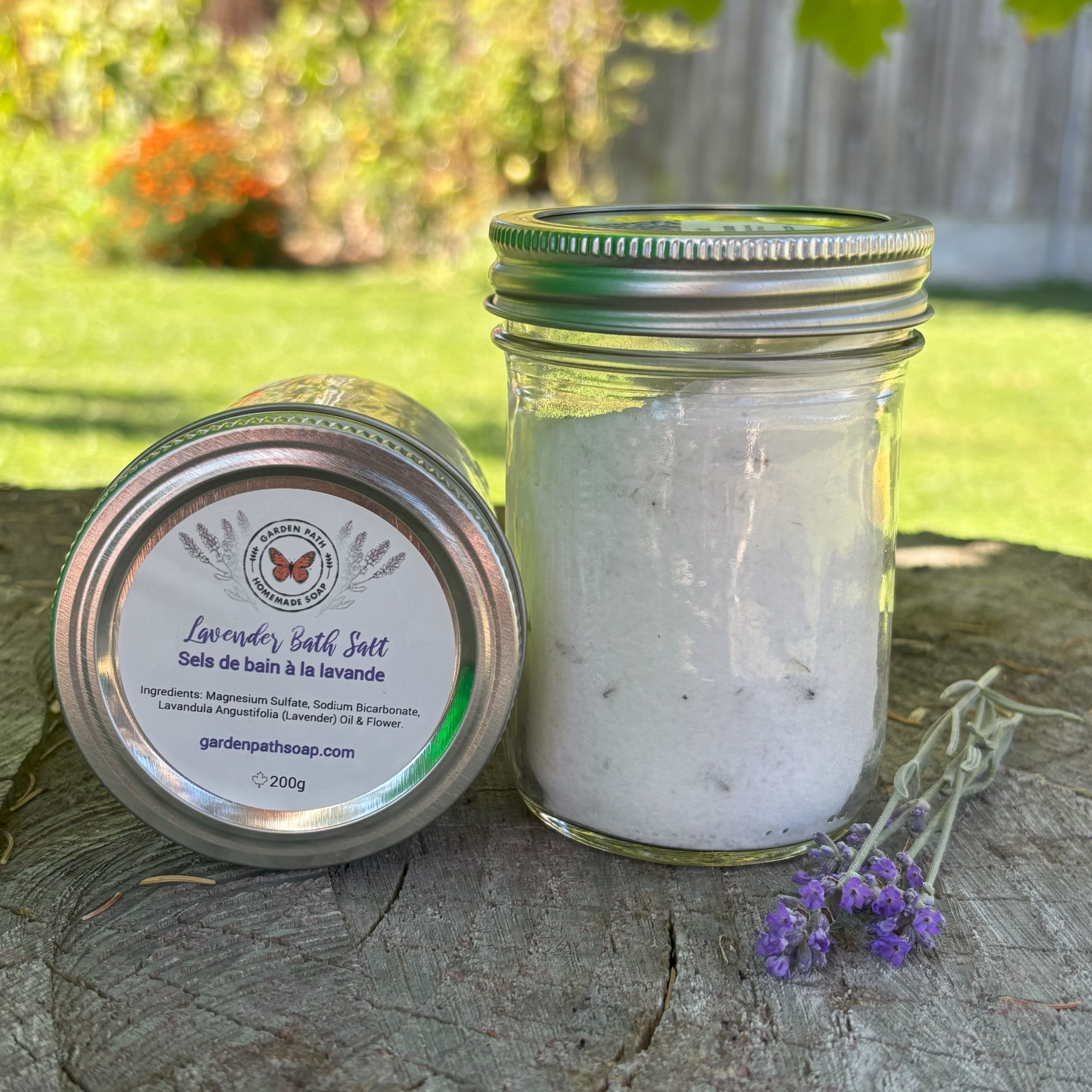 Jar of lavender bath salt with a label on a wooden surface outdoors by Garden Path Homemade Soap. 100% Natural Essential Oil & Ingredients