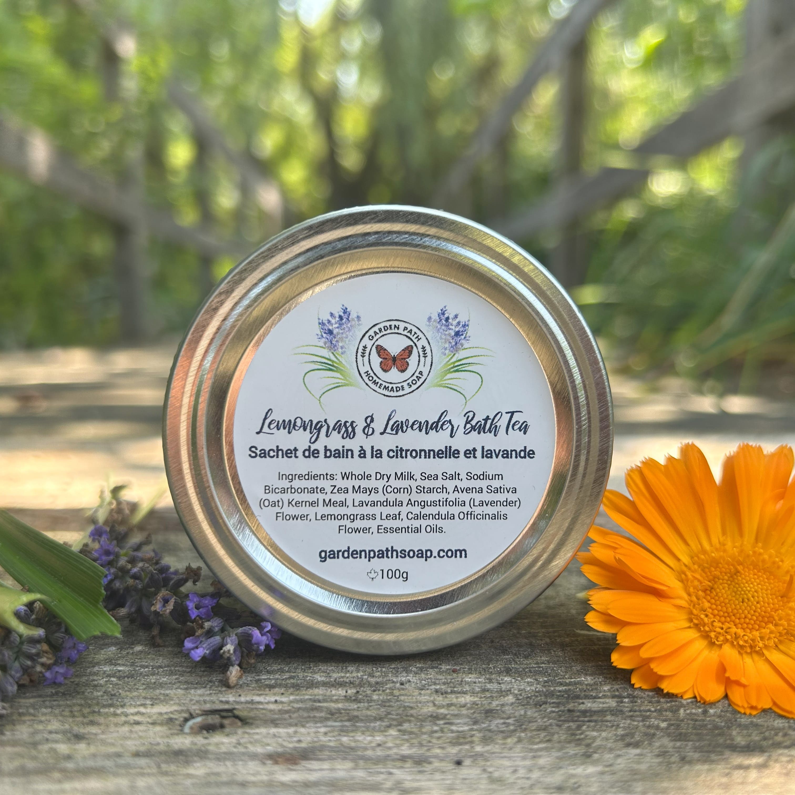 Bath tea container with lemongrass and lavender scent on a wooden surface with flowers and greenery in the background