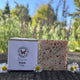 Rosacea Facial Bar of soap with packaging and flowers on a natural background by Garden Path Homemade Soap. 100% Natural Anti-Inflammatory Ingredients