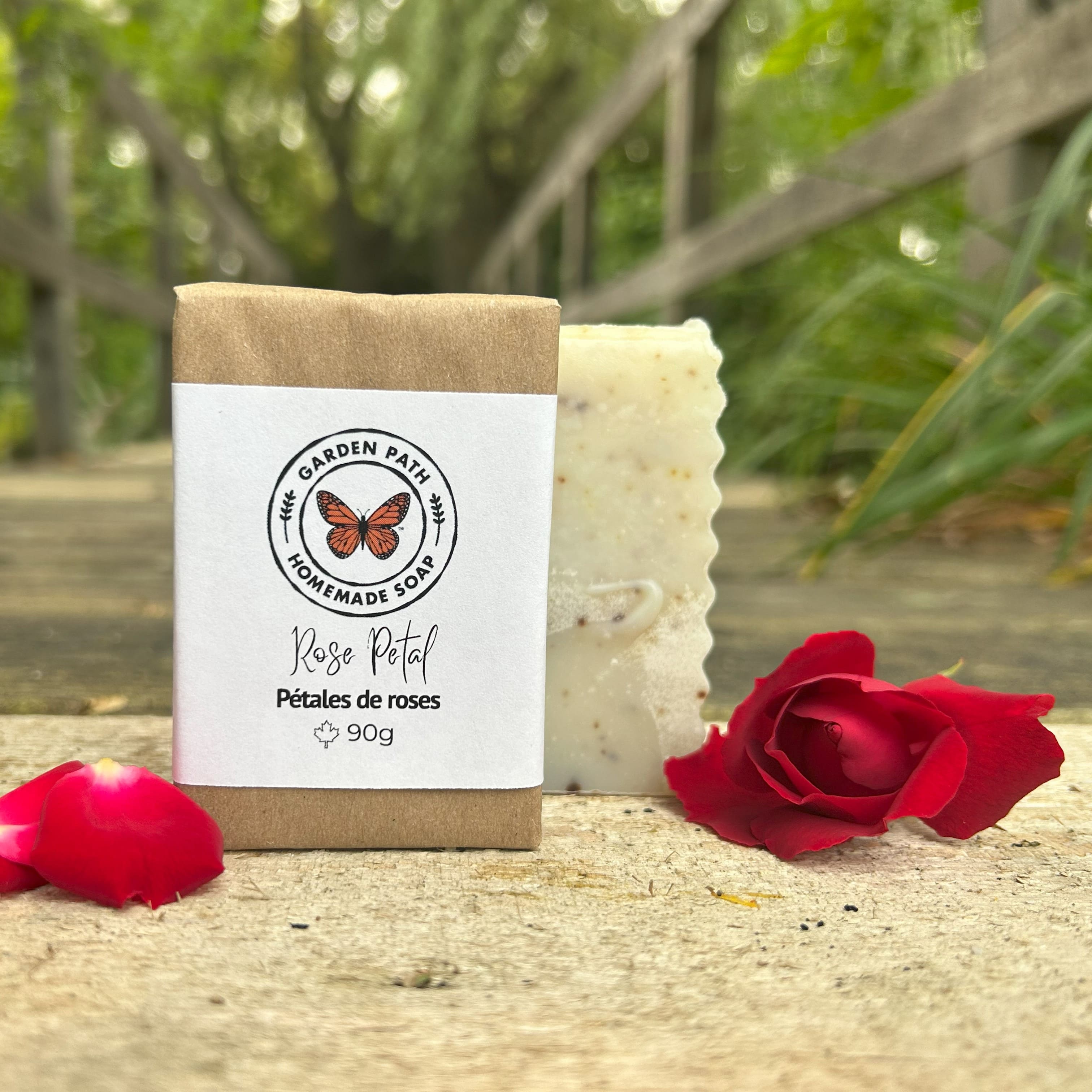 Rose Petal bar of soap with a 'Garden Path Homemade Soap' label, surrounded by red roses on a natural surface.  Lightly Scented Fragrance