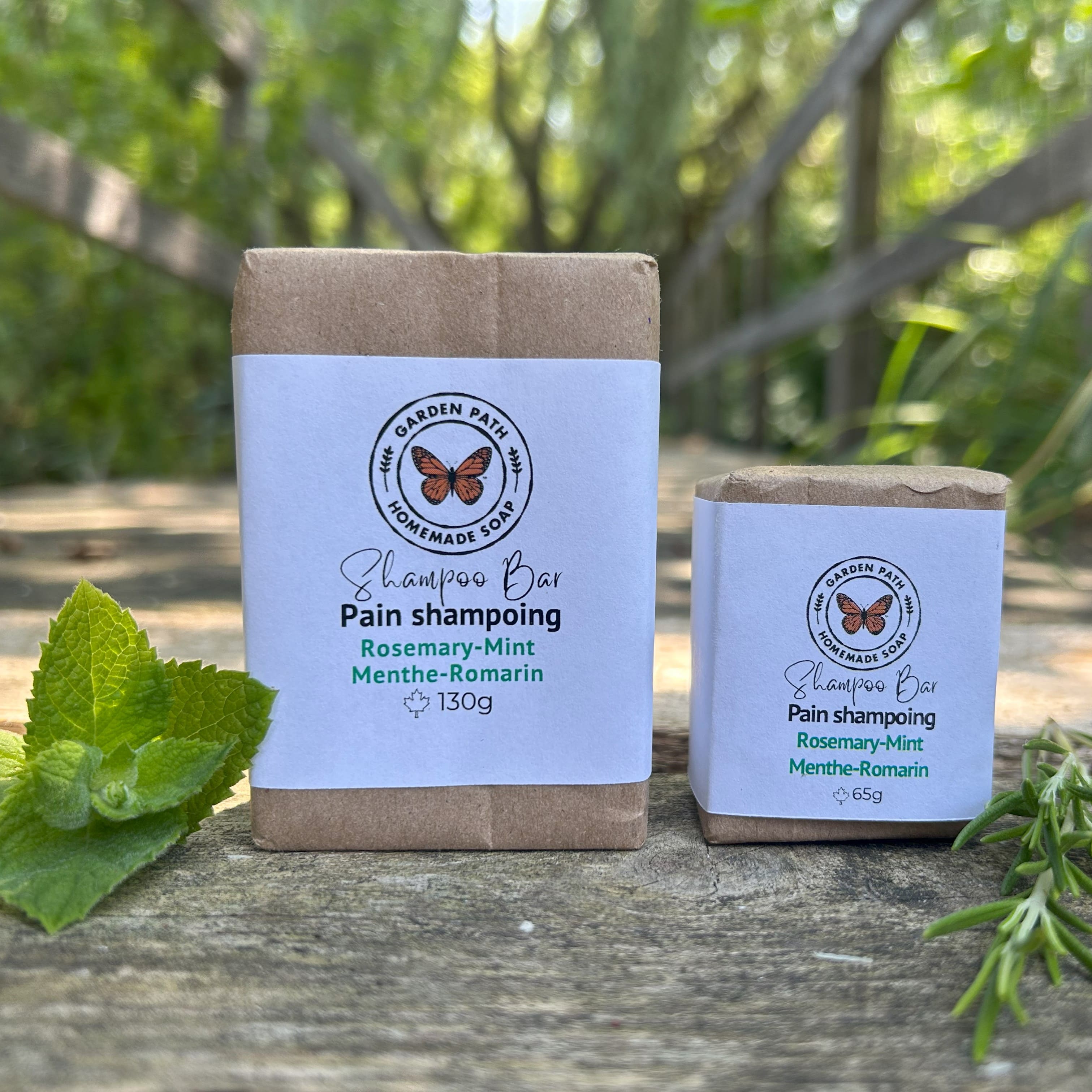 Rosemary Mint Shampoo Bar by Garden Path Homemade Soap - both large and small wrapped shampoo bars on a wooden surface with in and rosemary springs. 100% Natural Ingredients | Made with Beer