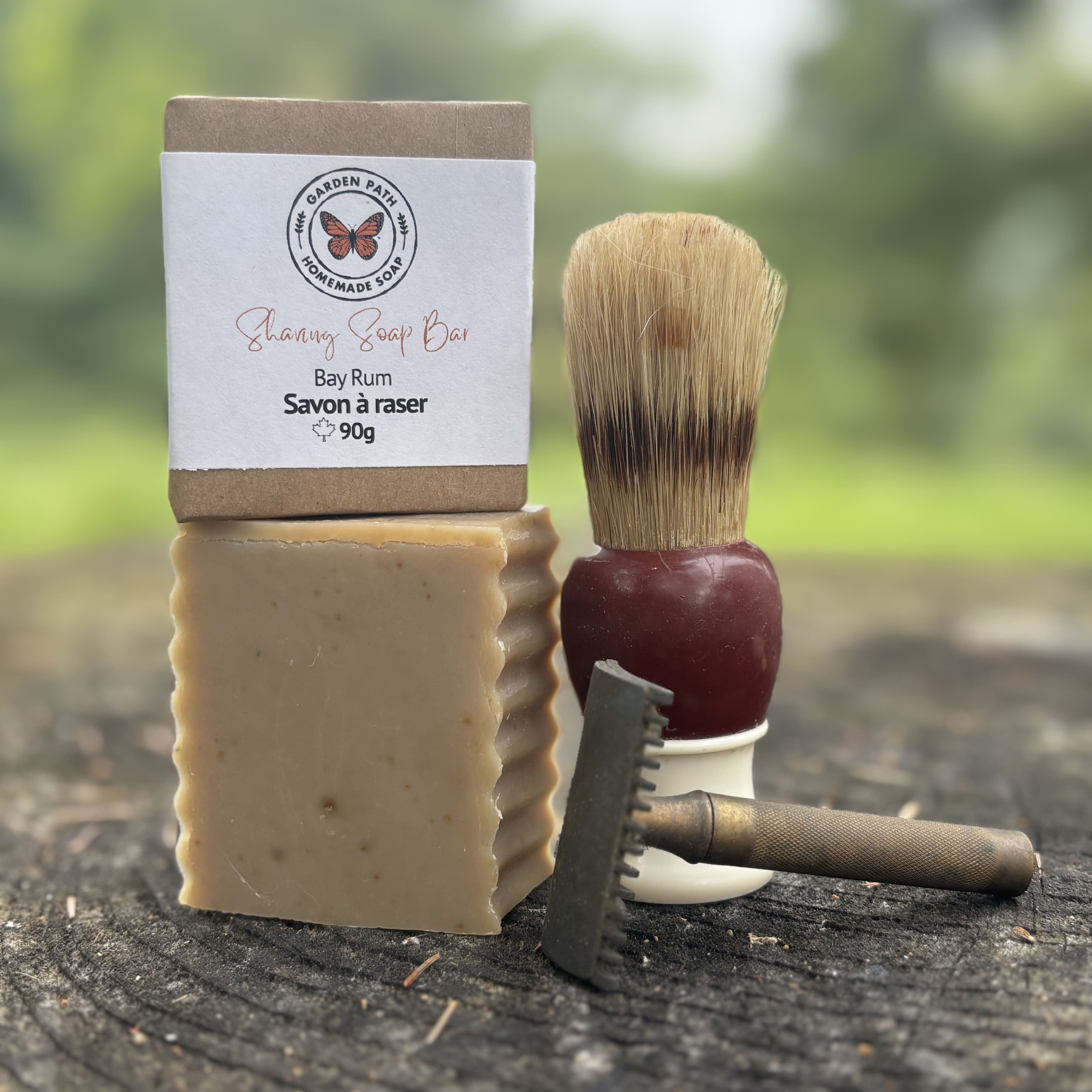 Shaving soap bar, brush, and razor on a wooden surface with a natural background