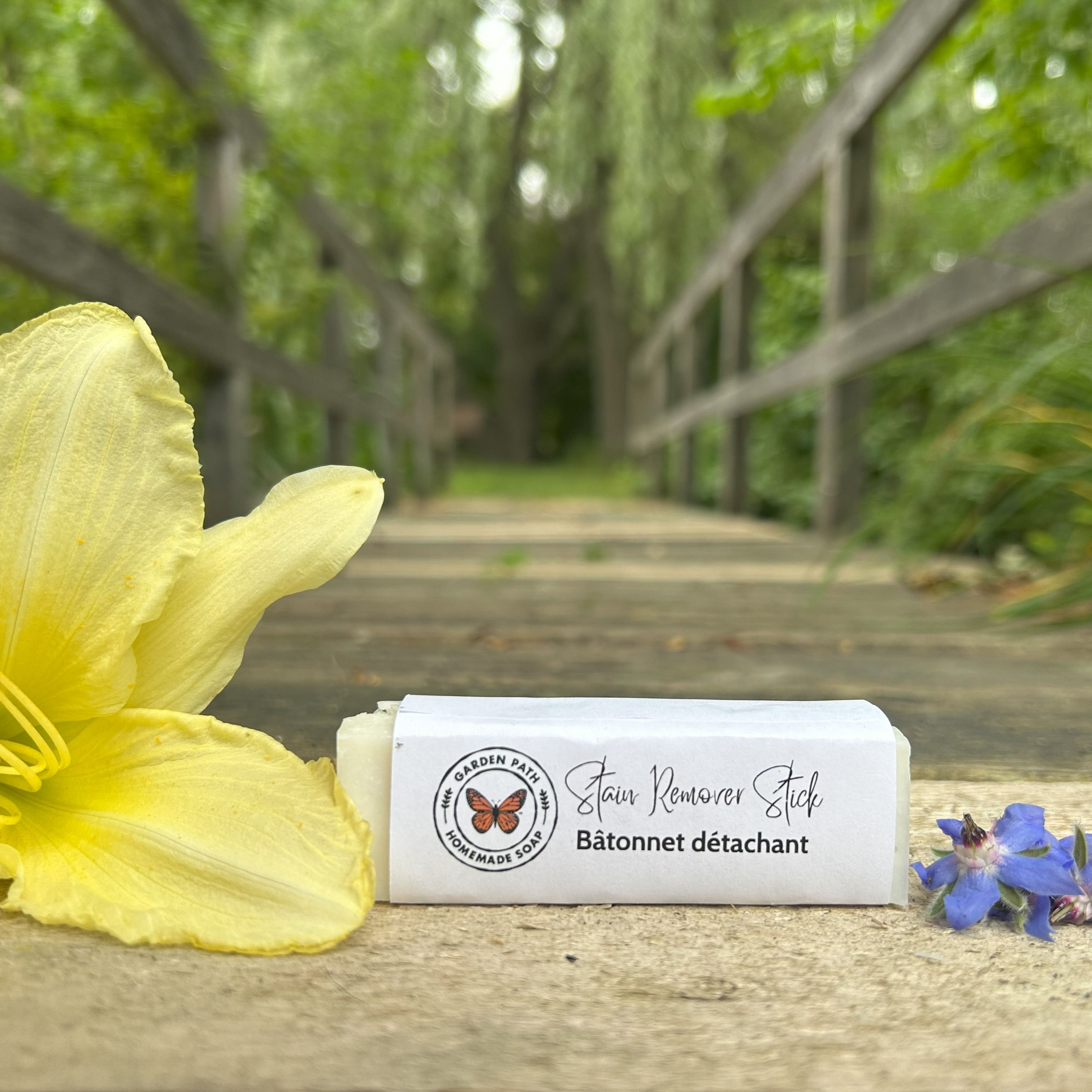 Garden Path Homemade Soap's Stain Remover Stick on wooden surface with yellow and blue flowers 