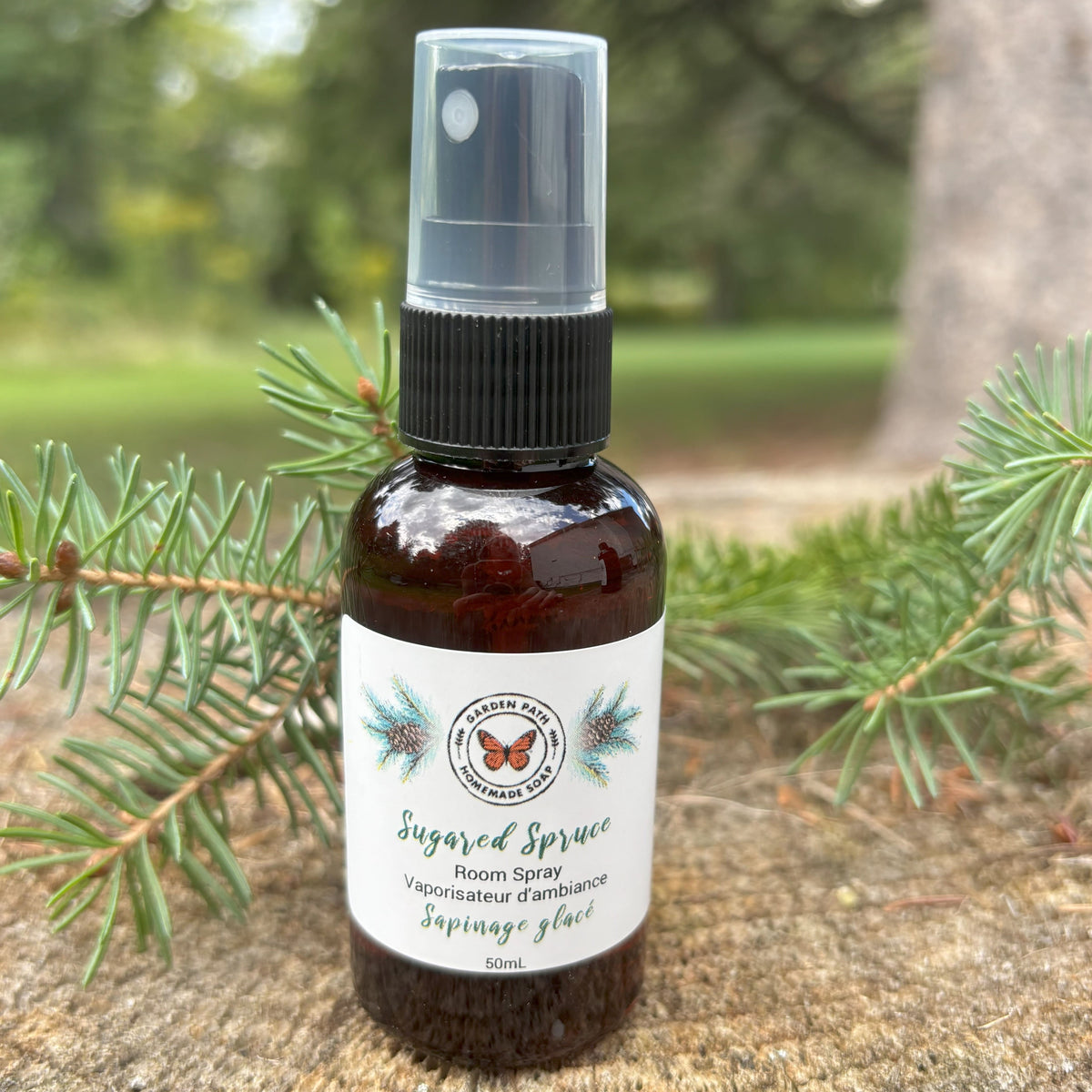 Sugared Spruce  Fragrance Oil Soap spray bottle on a wooden surface with green spruce  branches.