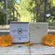 Wiggle Baby Bar both wrapped and unwrapped by Garden Path Homemade Soap sitting on a wooden  surface with calendula flowers. 100% Natural Ingredients | Unscented