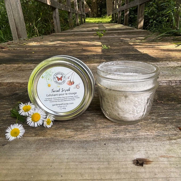 Jar of face scrub with a metal lid on a wooden surface with a natural background by Garden Path Homemade Soap.