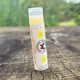 A stick of SPF lip balm  placed on a wooden surface with a natural background by Garden Path Homemade Soap. 100% Natural Ingredients