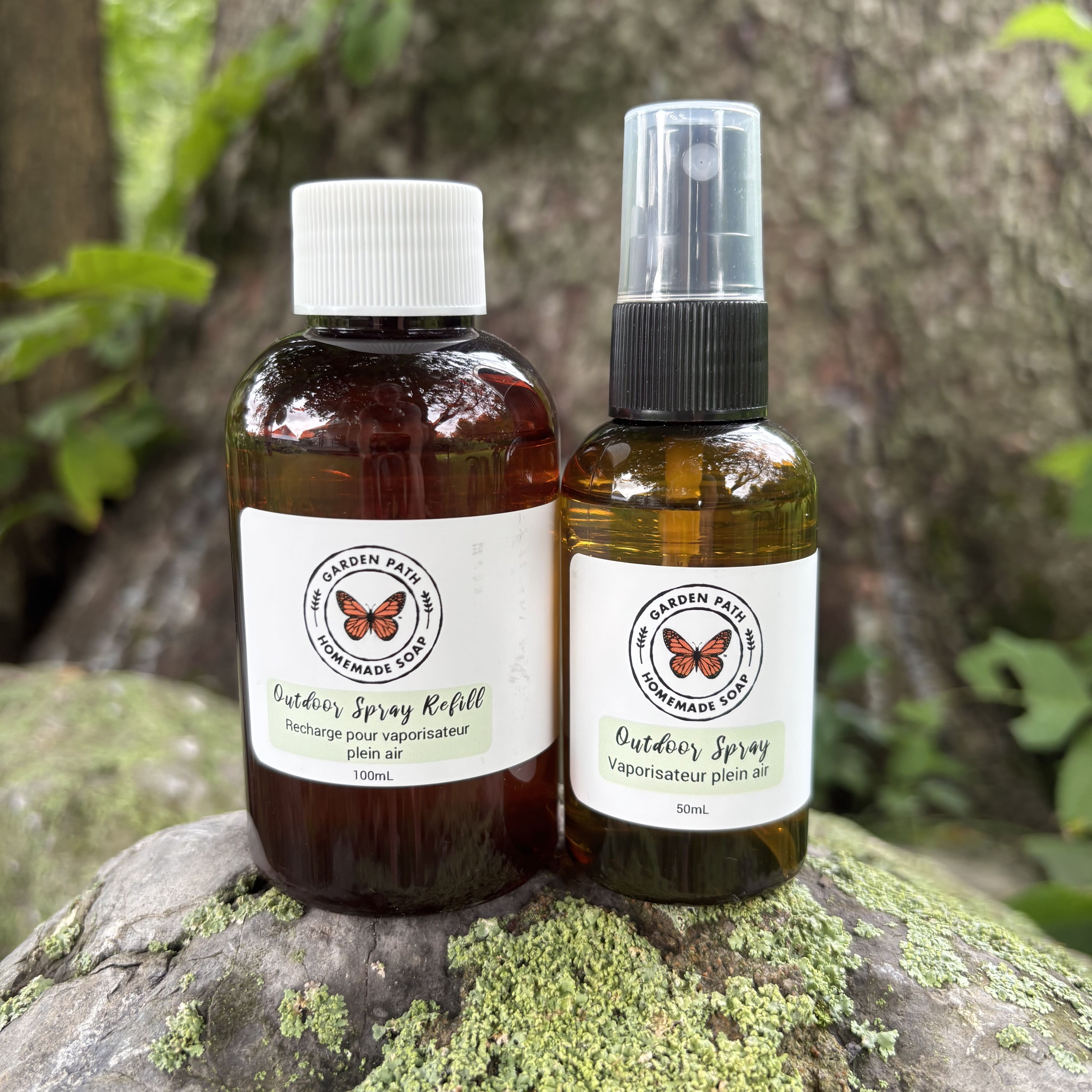 Outdoor Spray and refill bottle on a rock with lichen in an outdoor setting.   100% Natural Essential Oil Blend - Garden Path Homemade Soap