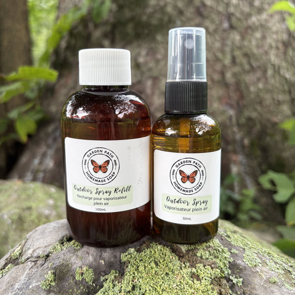 Outdoor Spray and refill bottle on a rock with lichen in an outdoor setting.   100% Natural Essential Oil Blend - Garden Path Homemade Soap