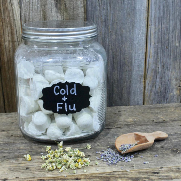 Jars filled with Cold & Flu shower tablets with dried lavender and chamomile on a wooden surface by Garden Path Homemade Soap.