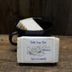 Dish Soap Bar sitting in front of a black mug that is also holding an unwrapped dish soap bar