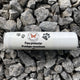 A roll-up tube of paw protector cream placed on a bed of rocks, with the product's branding and text visible on the tube.
